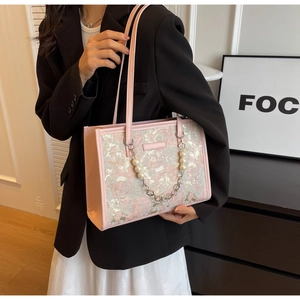 Détail du sac bandoulière rose gaufré avec perles et breloque chaîne en trèfle métal