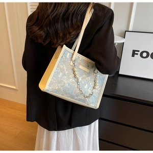 Détail du sac cabas en jacquard bleu avec motifs de chat et chaîne de perles élégante