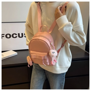 Pink mini backpack detail featuring a decorative bow, plush charm, and a small coin pouch