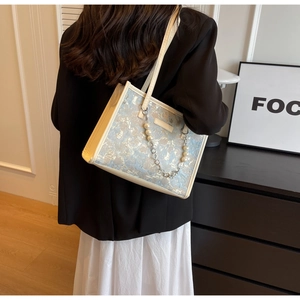 Détail du sac cabas élégant en jacquard avec motifs bleus et bandoulière en perles