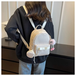 Detail of mini beige nylon backpack with bow decor and cute plush doll pendant