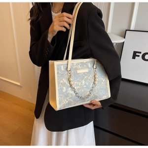 Détail du sac cabas en jacquard bleu clair avec lanières en cuir blanc et chaîne perles