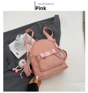 Pink nylon mini backpack with decorative ribbon bow and plush keychain details