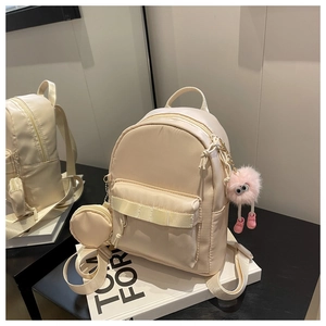 Detail of beige mini nylon backpack with matching round coin purse and plush monster charm