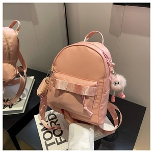 Pink nylon mini backpack with matching coin pouch and fuzzy monster keychain detail