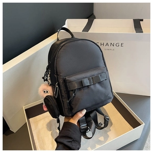 Mini black nylon backpack with bow detail, side coin purse, and pink plush charm accessory