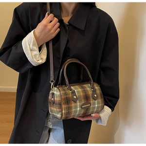 Detail of vintage Boston bag with brown plaid fabric and leather straps in a minimal setting