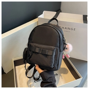 Mini black nylon backpack with bow detail and pink plush ball pendant shown in gift box