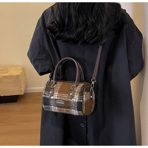 Detail of checkered tweed Boston bag with leather trim worn as a stylish crossbody bag