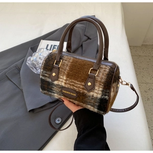 Close-up of winter boston bag with brown checkered plush texture and leather handle