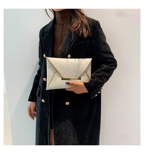 Dettaglio di una pochette a busta in trama intrecciata color crema con fibbia dorata