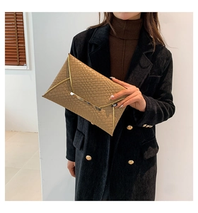 Dettaglio pochette a busta intrecciata caramello con elegante bordo in metallo dorato