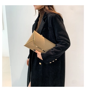 Dettaglio della pochette a busta intrecciata kaki con elegante bordo in metallo dorato