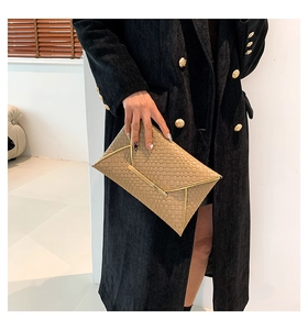 Dettaglio di una pochette a busta beige intrecciata con eleganti finiture dorate