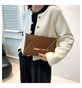 Dettaglio pochette a busta marrone scuro con trama intrecciata e bordo in metallo dorato