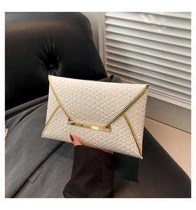 Dettaglio della pochette a busta bianca con trama intrecciata e bordo in metallo dorato