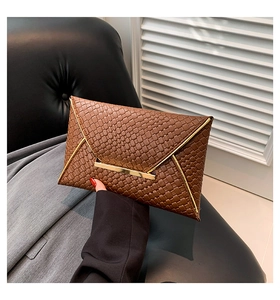 Dettaglio della pochette a busta intrecciata marrone con texture vintage e fibbia d'oro