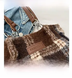 Macro shot of checkered wool tote bag with brown leather handles and metal rings