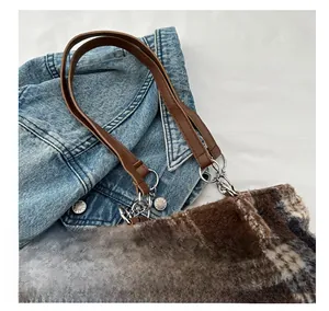 Close-up of checkered wool tote bag with brown leather straps and silver hardware