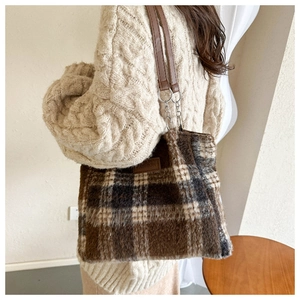 Close-up of brown and beige plaid plush tote bag with fashion leather tag and chain strap