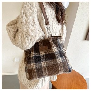 Detail of wool-like plaid tote bag showing fuzzy texture and leather strap on shoulder