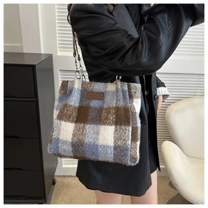 Detailed close-up of a plaid wool tote bag featuring a leather fashion patch and chain strap
