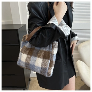 Close-up of wool plaid bucket bag showing plush texture and brown leather handle