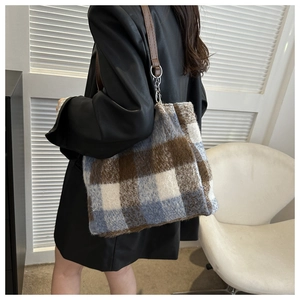 Detail of soft plaid tote bag in blue and brown wool with leather straps and silver rings