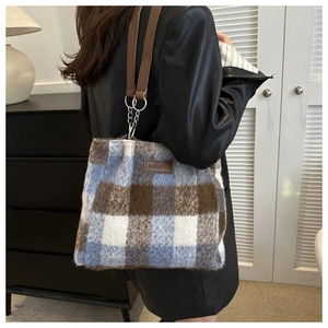 Close-up of blue plaid wool tote bag featuring a leather strap and metallic chain link