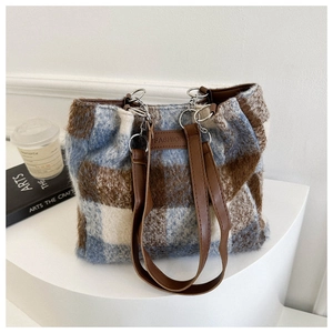 Close-up of fluffy plaid tote bag featuring blue checkered wool and brown leather handles