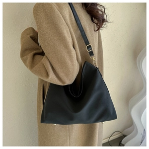 Model wearing a large matte black hobo tote bag with gold hardware and adjustable strap