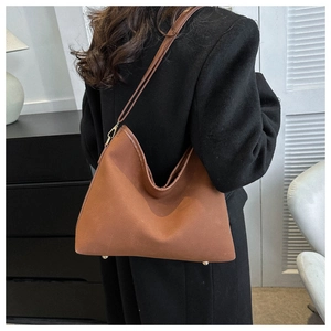 Brown leather hobo bag with fine matte texture and golden hardware shown on a model