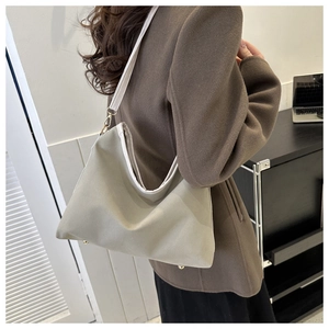Detail of canvas tote bag showing green fabric, white piping, and gold metal hardware