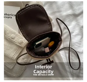 Détail de l'intérieur d'un sac bandoulière en peluche avec téléphone et rouge à lèvres