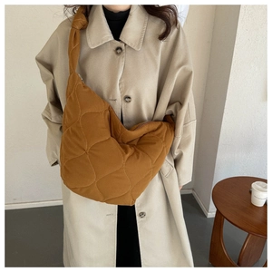 Close-up of ginger yellow quilted hobo bag with thick shoulder strap and diamond stitching
