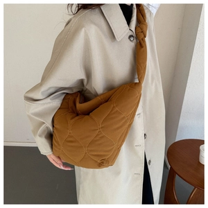 Close-up of caramel quilted crossbody bag featuring wave patterns and stylish knotted strap