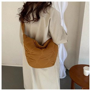 Detail of ginger brown quilted crescent bag showing stitching and wide shoulder strap