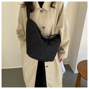 Detail shot of black quilted cloud bag showing knot shoulder strap and nylon fabric texture