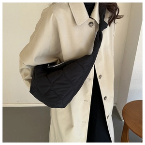 Detail of black quilted puffer tote bag with knot strap and zipper closure