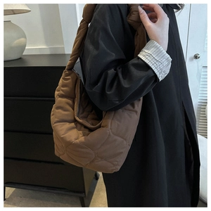 Detail of a brown quilted nylon shoulder bag featuring a stylish knotted wide strap design