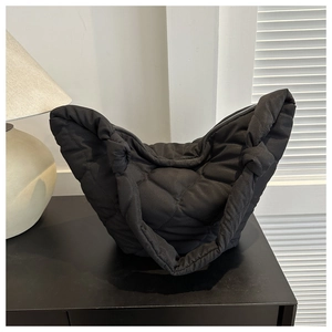 Detail of black quilted cloud bag showing unique knot shoulder strap and puffy texture