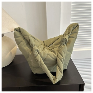 Detail of sage green quilted tote bag with wave stitching and knotted strap design