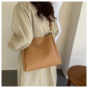 Détail du sac à bandoulière camel avec bandoulière à nœud élégante porté par le mannequin