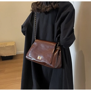 Detail of vintage dark brown faux leather shoulder bag with golden metallic twist lock