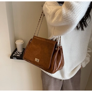 Detail of vintage brown leather bag with golden twist lock and chain shoulder strap