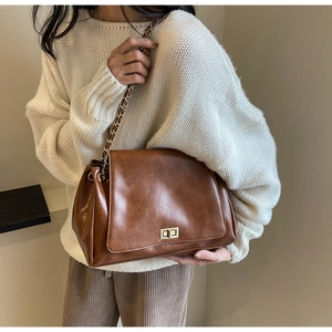 Detail of vintage brown leather shoulder bag with gold metal twist lock and chain strap