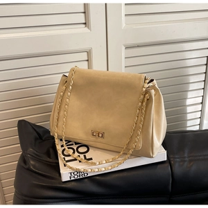 Close-up of beige leather shoulder bag featuring gold twist lock and chain strap detail