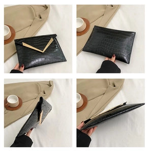Detail view of black crocodile pattern envelope clutch bag with gold V-metal logo
