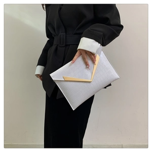 Close-up of a white crocodile texture clutch bag with a gold V-shaped metal accent