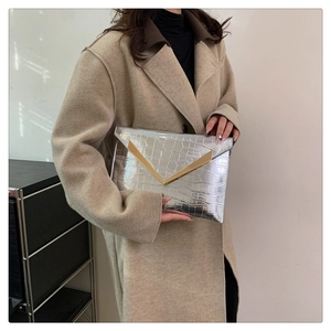 Detailed close-up of silver crocodile pattern clutch bag with gold V-shaped metal trim
